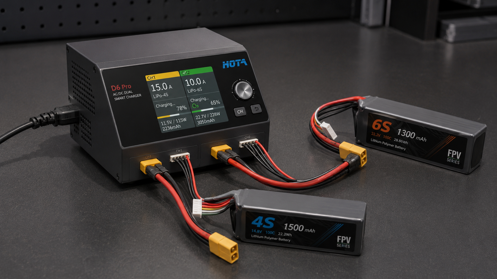 HOTA D6 Pro dual-channel FPV LiPo charger connected to two battery packs on a workbench