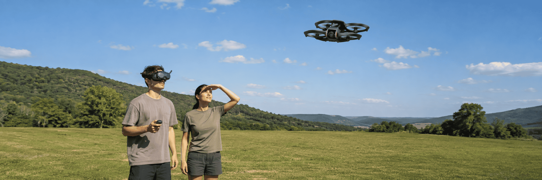A DJI Avata 2 pilot wearing goggles flies beside a visual observer watching the aircraft in an open field.