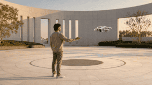 Compact camera drone responding to an open-palm gesture in a circular architectural plaza.