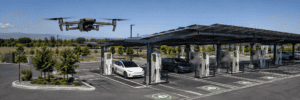 Drone surveying an EV charging site with charging pedestals and a solar canopy.