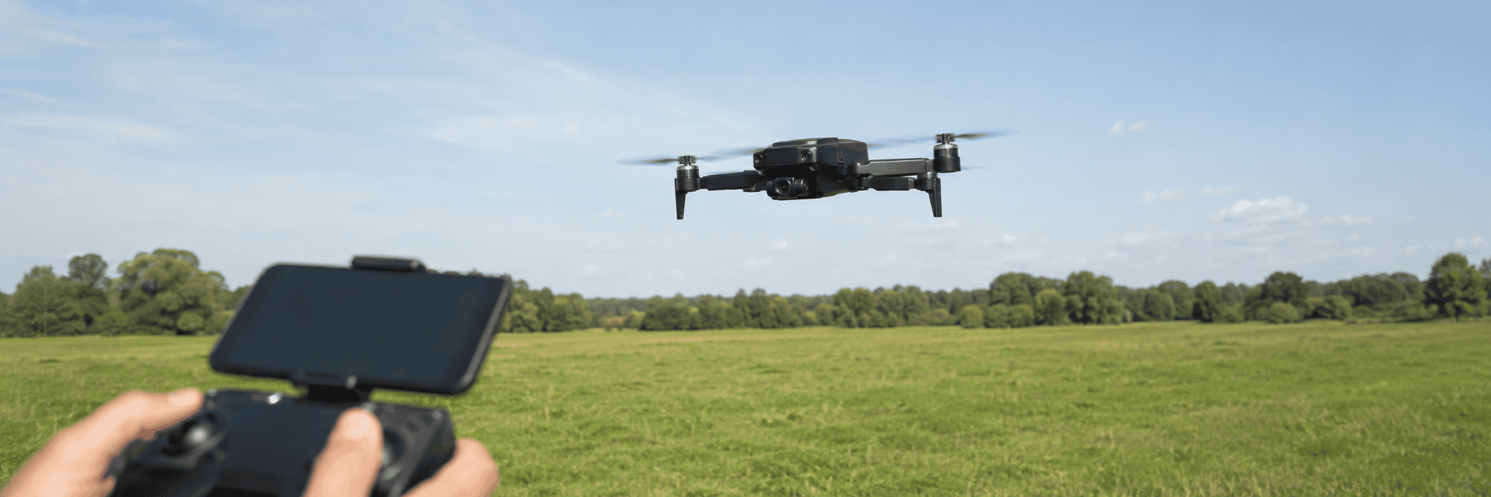 Black Holy Stone HS360S flying over an open grassy field.