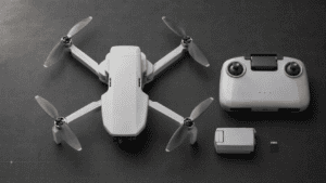 Compact gray folding drone beside its controller, battery, and microSD card on a technical work surface.