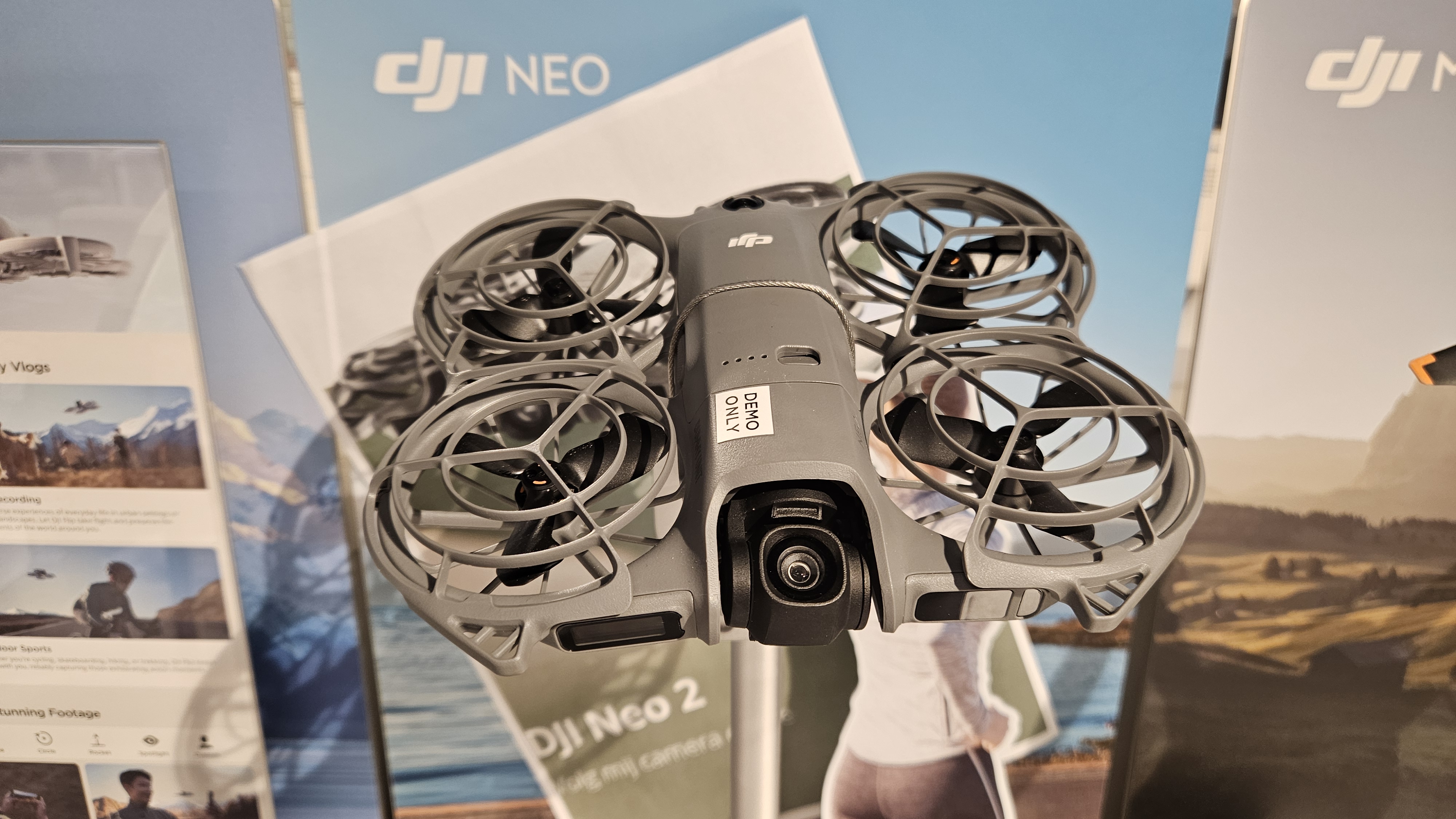 DJI Neo 2 demonstration aircraft in a shop, with camera, front sensors and propeller guards visible.